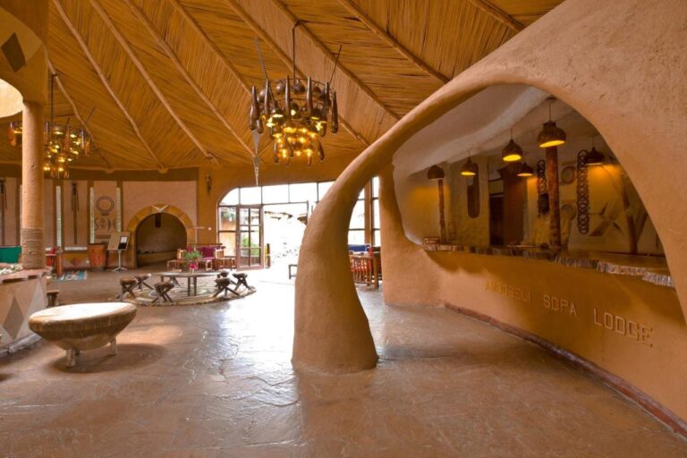 Resepsjonsdisken i formet leire, med navnet Amboseli Sopa Lodge risset inn, under et tak av siv