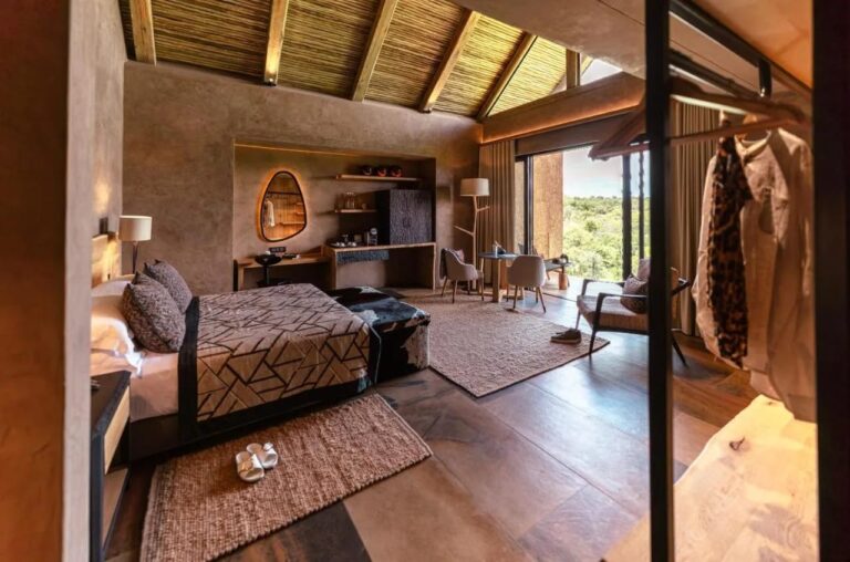 En suite på Kapama River Lodge under en takkonstruksjon av tre og strå, med arbeidskrok og utsikt mot trærne