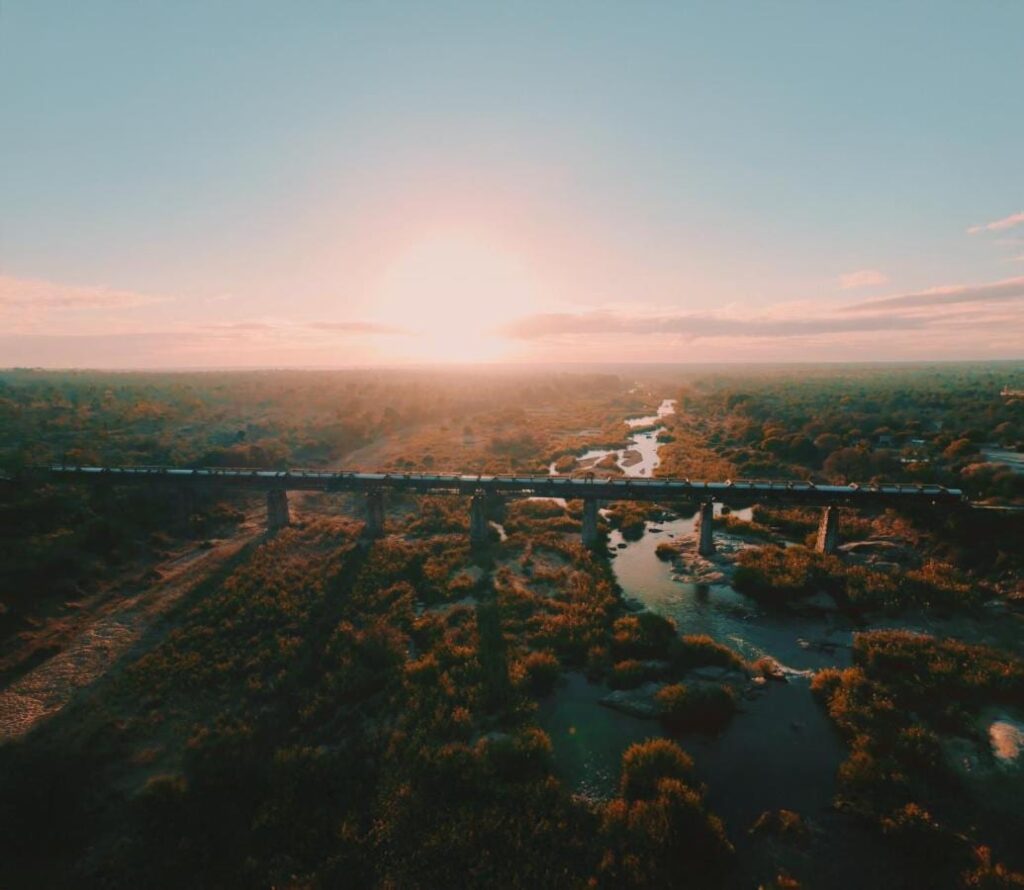 Toget til Kruger Shalati på Selati-brua, sett fra luften, over elva og bushen, med lav sol i horisonten