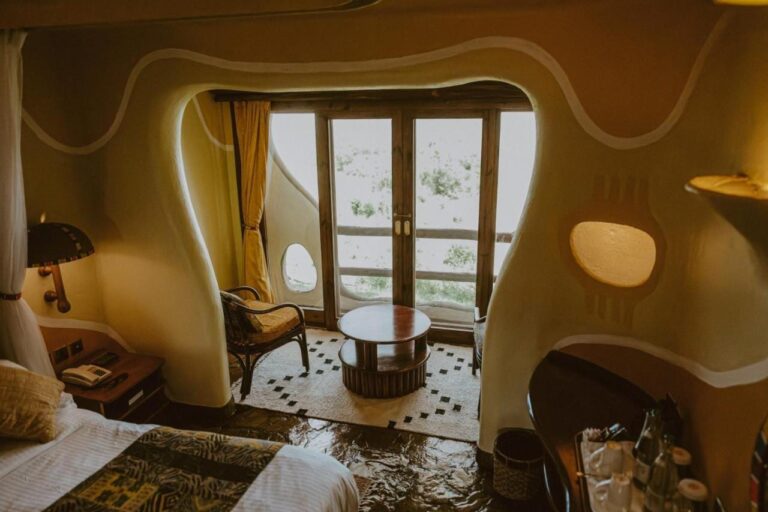 Et rom med avrundede vegger på Mara Serena Safari Lodge, med sittegruppe foran balkongdøra