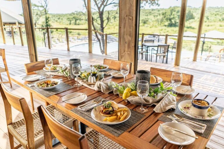 Et dekket bord i restauranten, som åpner seg mot terrassen, bassenget og bushen