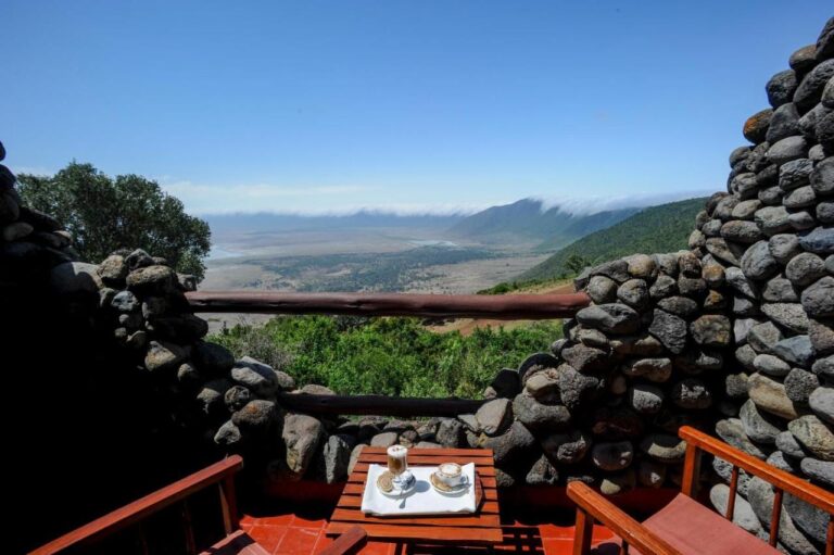 To kopper kaffe på en balkong på Ngorongoro Serena Safari Lodge, mellom steinmurer, over krateret