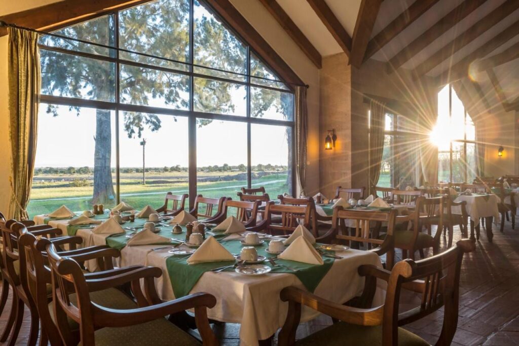 Restauranten på Sweetwaters Serena Camp, med dekkede bord foran en stor glassvegg mot sletta