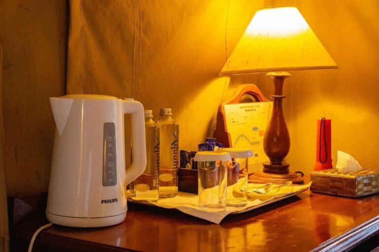 En vannkoker, vannflasker og glass på et skrivebord, under en lampe